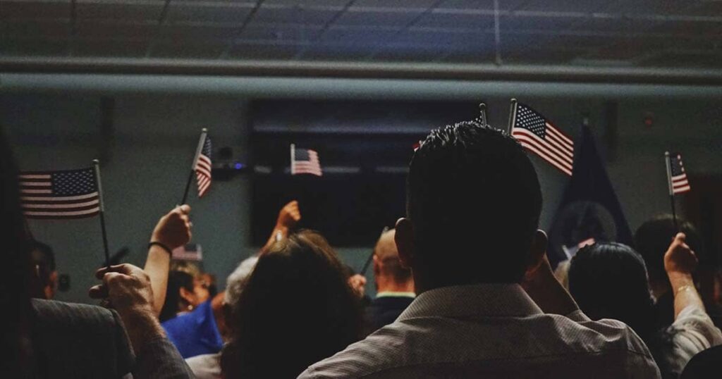 Inmigrantes alzando la bandera de estados unidos en las oficinas de migración