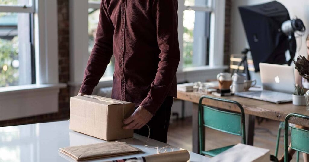 Hombre trabajando desde casa empacando productos en una caja